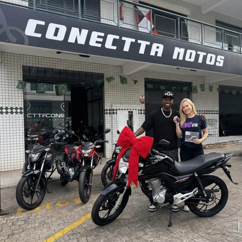 Clientes recebendo a chave da Honda Fan 160cc na fachada da Conectta Motos em Goiânia